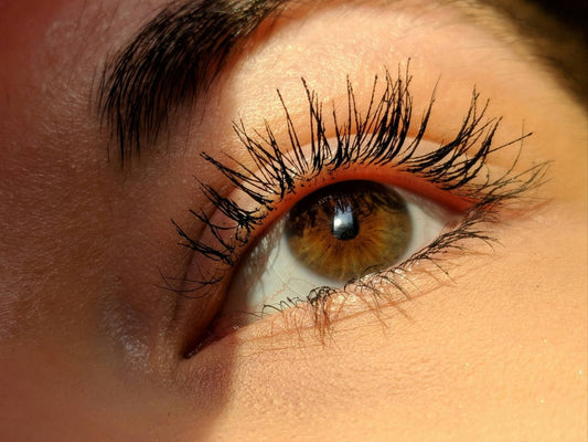 How to get thicker lashes with natural growth tips. Picture of woman's eye and thick healthy lashes. Unfurl