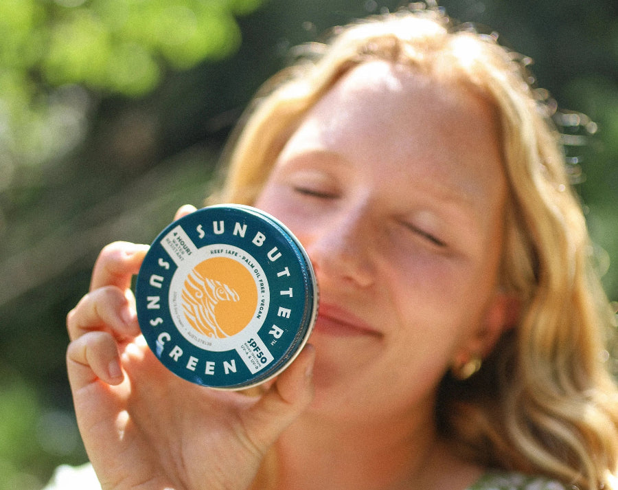 Women in the sun holding sunbutter chemical free sunscreen tin