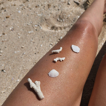 Coral fragments on a person's leg with sparkly sunscreen and sand in the background