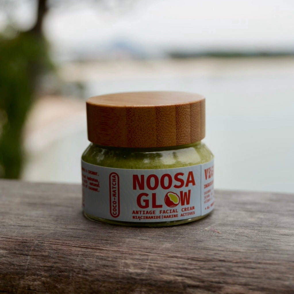 Jar of Noosa Glow anti-gaing facial cream on a wooden surface with a blurred natural background
