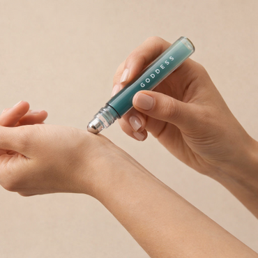Hand holding a roller of natural fragrance labelled 'GODDESS' onto a a wrist. 
